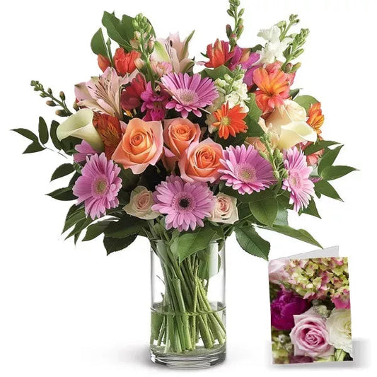 Bouquet of assorted flowers in a glass vase with a small card.