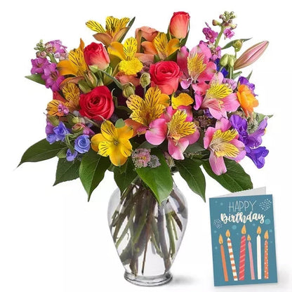 A colorful bouquet of mixed flowers in a vase with a 'Happy Birthday' card.