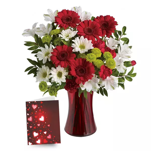 Bouquet of red and white flowers in a red vase with a heart-themed card.