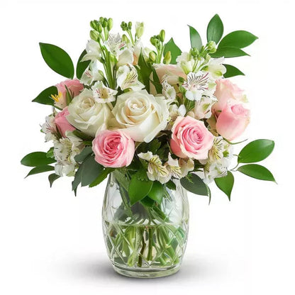A bouquet of white and pink roses with greenery in a clear glass vase.