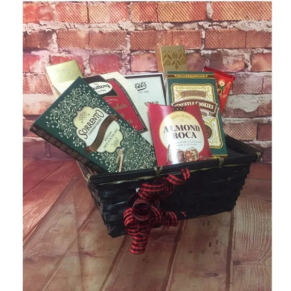 A gift basket with assorted chocolates and cookies against a brick wall background.