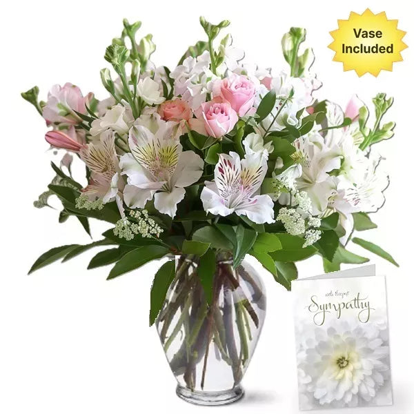 A bouquet of pink roses and white alstroemeria in a vase with a "With Sympathy" card.