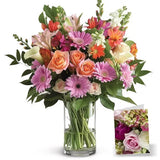 Bouquet of assorted flowers in a glass vase with a small card.