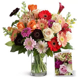 Bouquet of colorful roses and gerberas in glass vase with card.