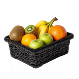 Assorted fruits in a black wicker basket on a white background.