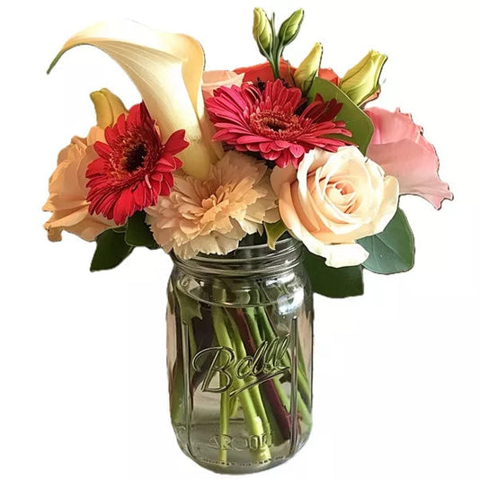 Bouquet of mixed flowers in a mason jar, including roses and lilies.